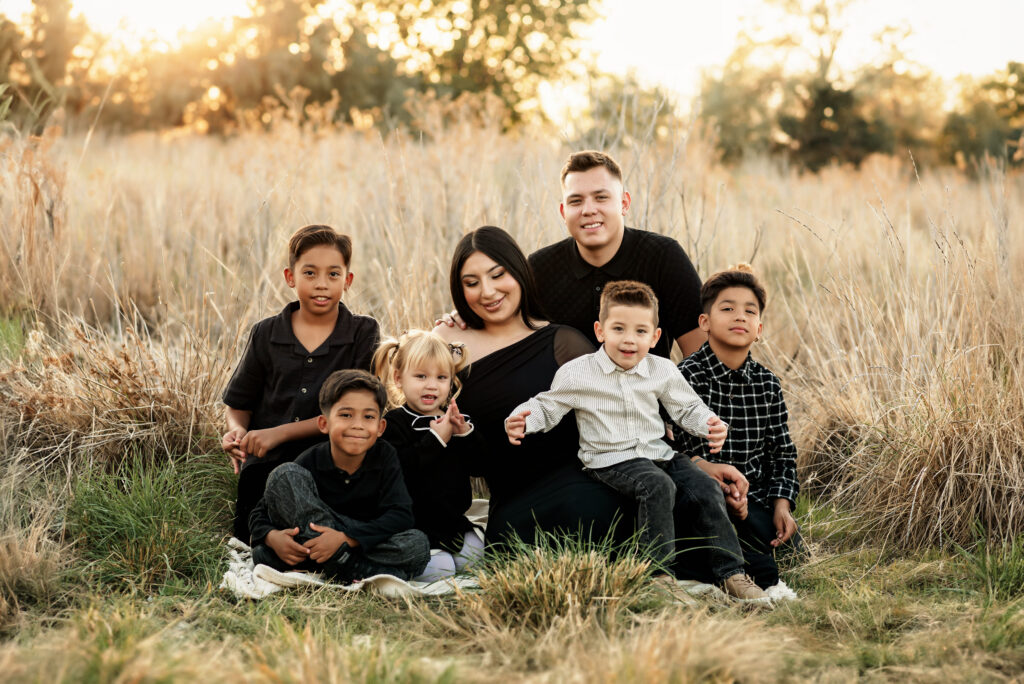 Natural family portrait showing parents and kids hugging in a picturesque Saratoga Springs field at sunset, highlighting genuine family connections