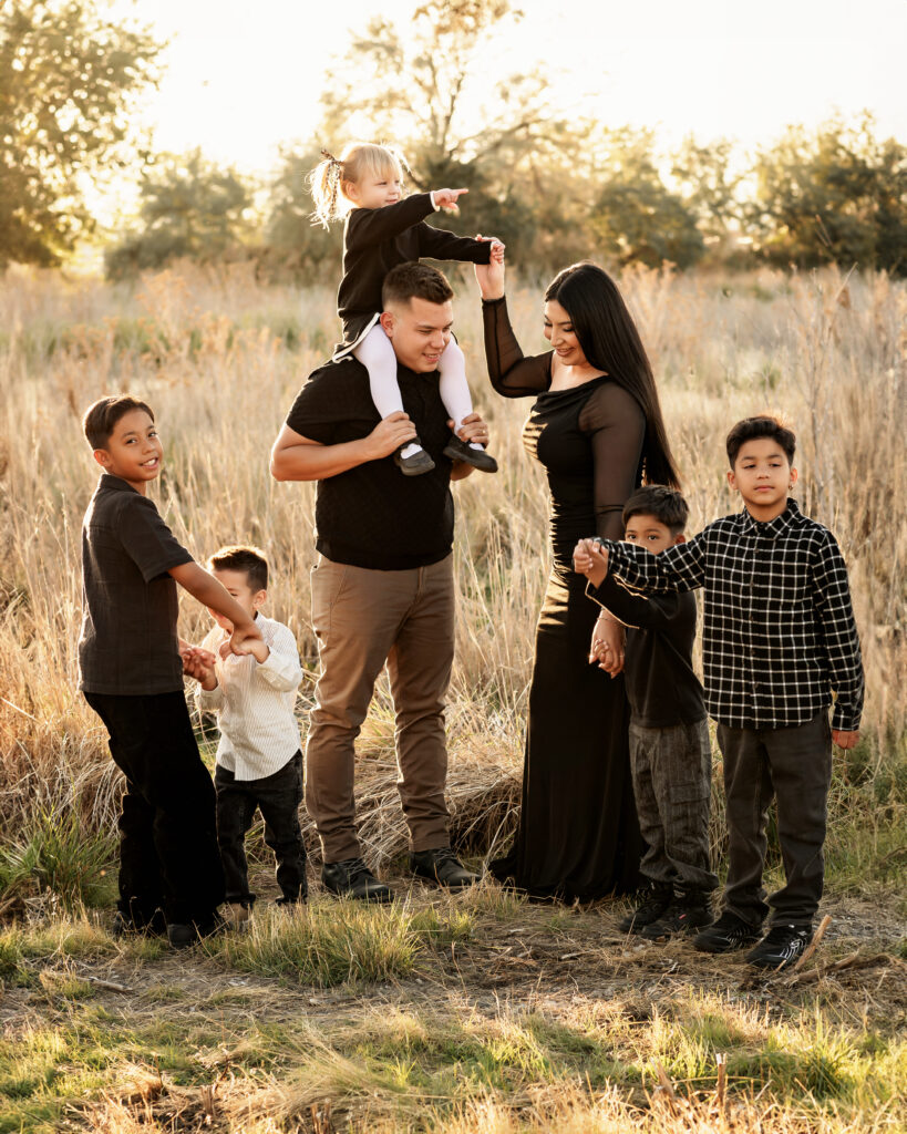 Professional posed family photo with parents and five kids, dressed in coordinated outfits, set against the scenic backdrop of Saratoga Springs, Utah